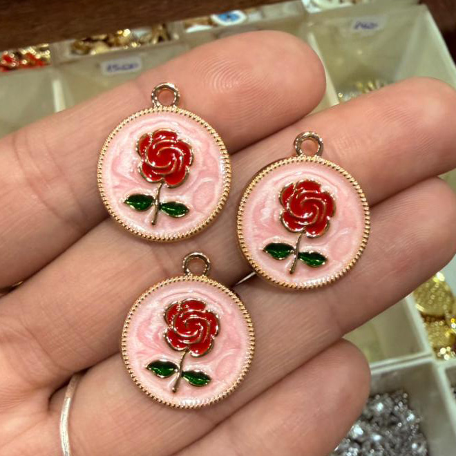 Dije esmaltado dorado flor roja con fondo rosa